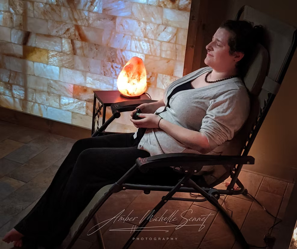 Client relaxing in a salt therapy chair surrounded by Himalayan salt walls